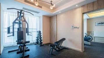A gym with exercise equipment, a bench, and a mirror.