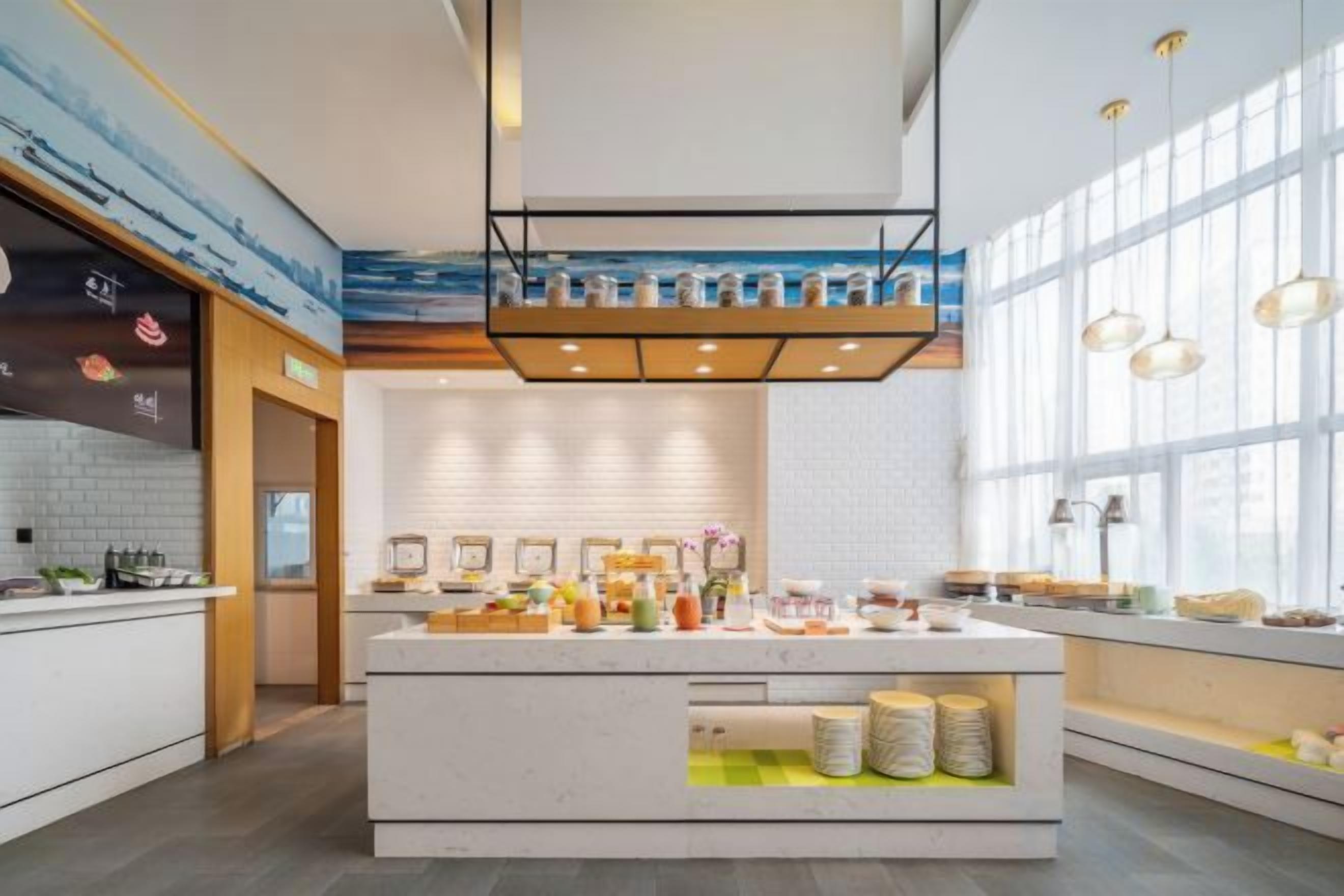 A modern kitchen with a central island, large windows, and pendant lighting.
