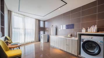 Une chambre d’hôtel moderne dotée d’un coin cuisine, comprenant un lave-linge, une table à manger et une chaise.