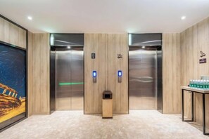 A modern elevator with two buttons, a digital display, and a small trash bin. - Xincheng Hotel (Yantai University International Expo Center Branch) (Yantai)