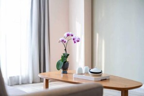 A wooden table with a vase of flowers, a tray with salt and pepper shakers, and a white object, possibly a tea set, in a room with a large window and curtains. - Xincheng Hotel (Yantai University International Expo Center Branch) (Yantai)