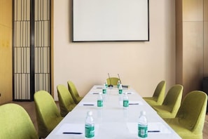 A conference room with a long table, green chairs, and water bottles. - Xincheng Hotel (Yantai University International Expo Center Branch) (Yantai)