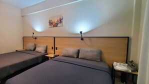 A hotel room with two single beds, a small table with a lamp, and a wall-mounted artwork. - Waterland Suites (Paramaribo)