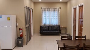 A compact living space with a kitchenette, a sofa, a dining table with chairs, and a window with curtains. - Waterland Suites (Paramaribo)