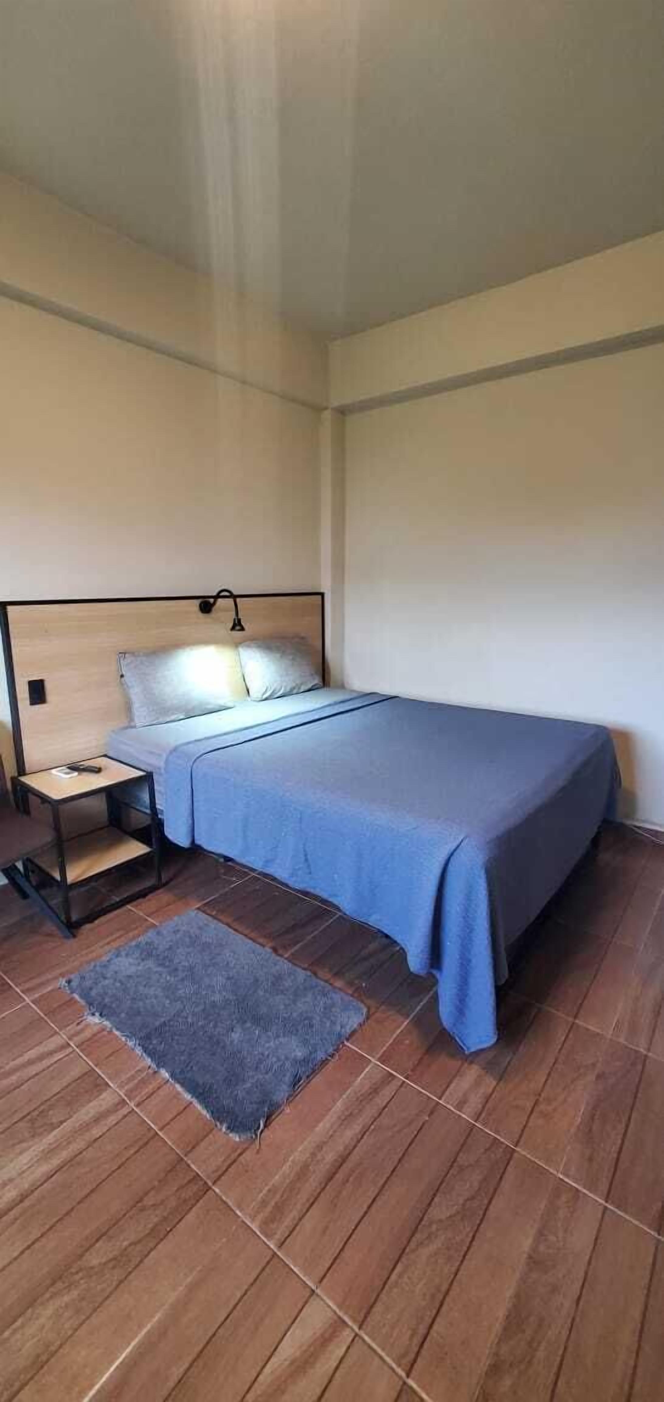 A bedroom with a bed, nightstand, and a small rug.