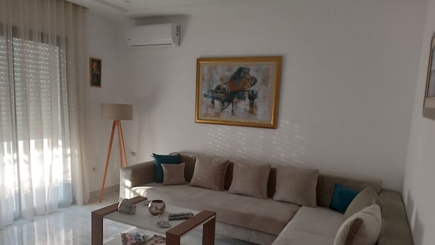 Un salon moderne avec un canapé beige, une table basse et un tableau accroché au mur.