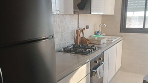 Une cuisine moderne avec un réfrigérateur noir, des appareils électroménagers en acier inoxydable et des carreaux décorés.