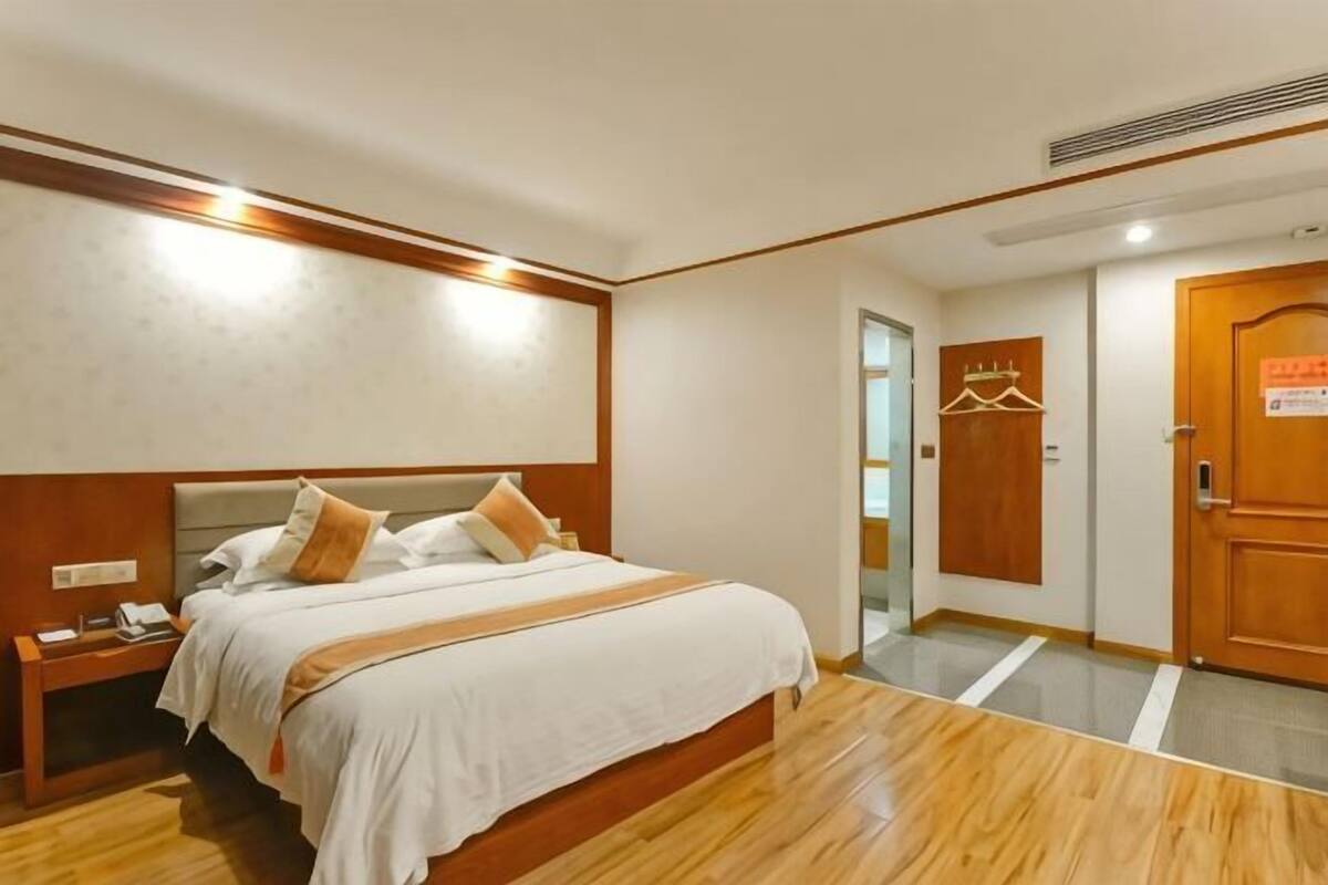 A hotel room with a bed, bedside table, and a door to the bathroom.