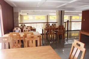 A dining area with wooden tables and chairs, a glass partition, and a view of the outside through windows. - NOMC Hotel (Xianju)