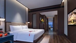 A modern hotel room with a large bed, a desk, and a view through an open door. - NOMC Hotel (Xianju)