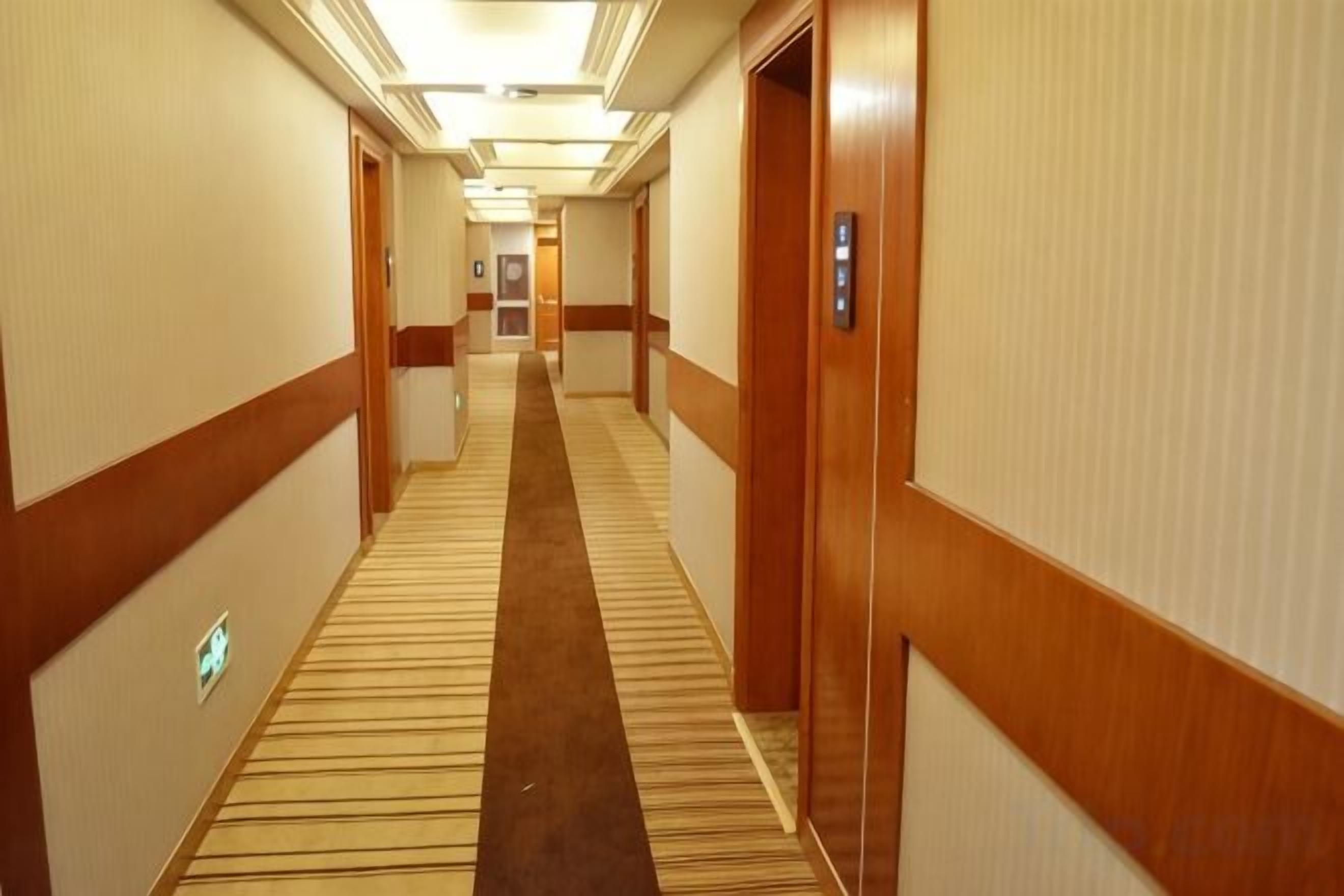 Un pasillo de hotel con pisos alfombrados, puertas de madera y un pasillo central también alfombrado.