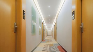 A hotel hallway with wooden doors, a patterned carpet, and recessed lighting. - Shankee Hotel (Nanjing South Railway Station Shuanglong Avenue Subway Station) (Nanjing)