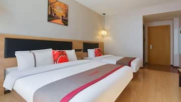 Quarto de hotel com duas camas, cabeceira, um quadro na parede e uma porta.