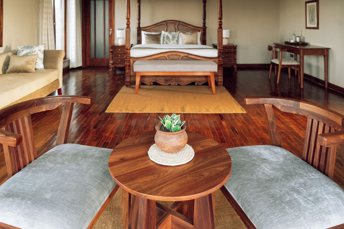 A spacious bedroom with a four-poster bed, a wooden coffee table with a plant, and a small side table.