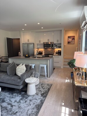 A modern living room with a grey sofa, a small white table, and a grey rug.