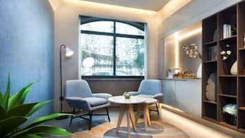 Quarto moderno com uma mesa redonda, duas cadeiras, uma estante e uma janela grande.