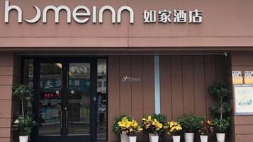 Entrada de hotel com uma placa indicando 'homeinn' e '如家酒店'.