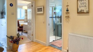 A hallway with wooden flooring, a potted plant, a framed picture, and a sign on the wall. - Escape to a cosy coastal retreat in Montrose, where you can unwind in style. (Montrose)