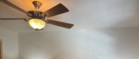 A bedroom with a bed, two nightstands, a ceiling fan, and two lamps.