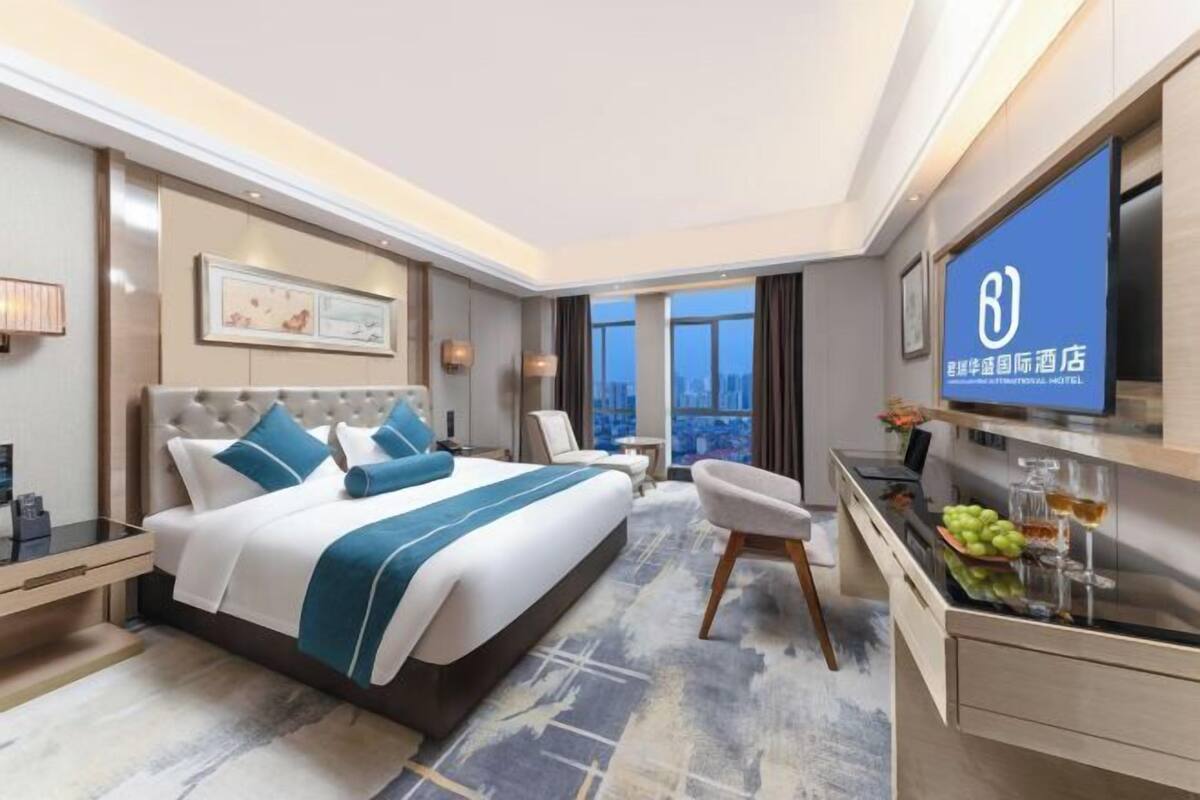 A modern hotel room with a large bed, a desk, and a TV.