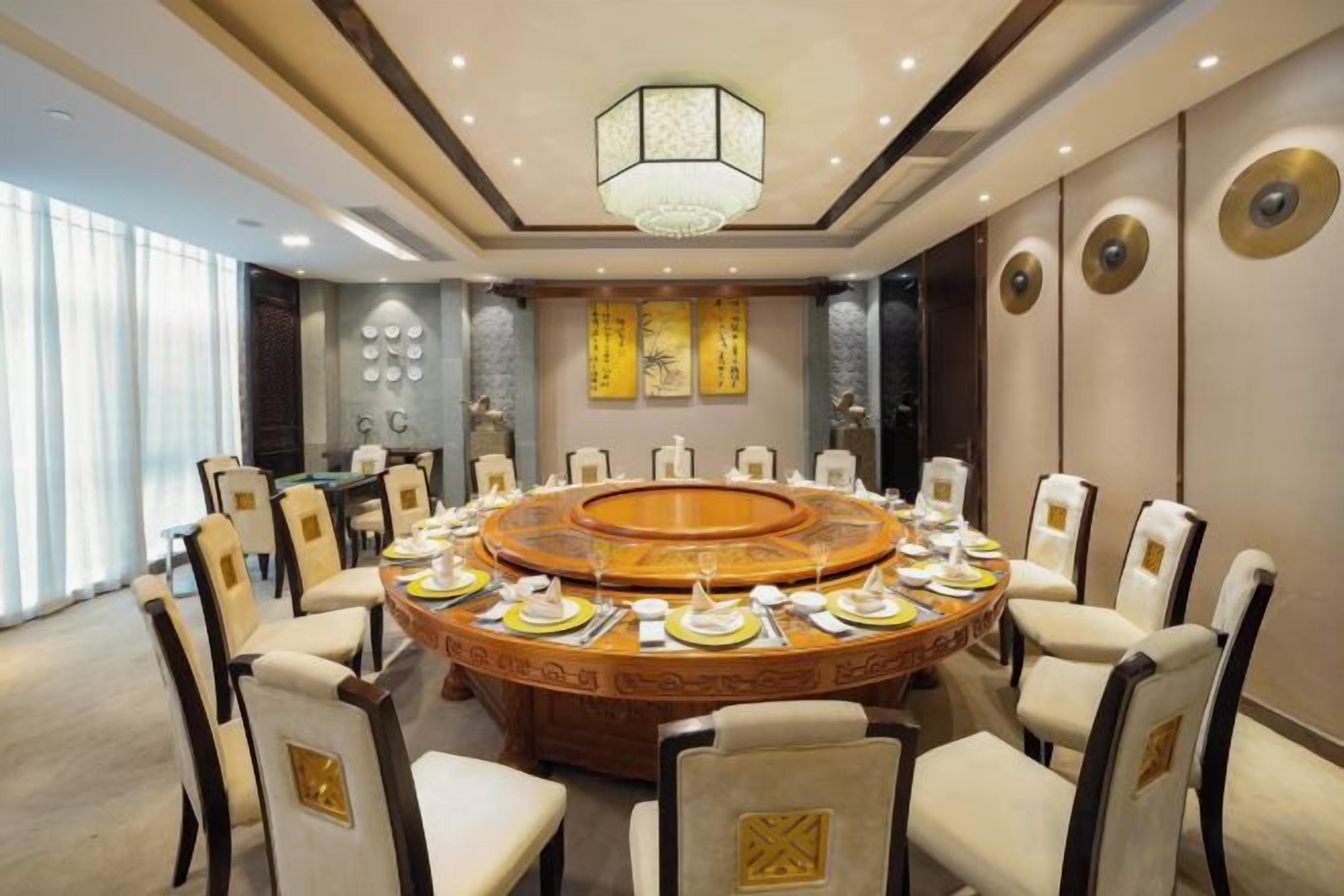 Un salón de conferencias con una mesa redonda, sillas y un candelabro.