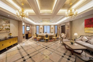 Una habitación amplia con una mesa redonda grande, elegantes candelabros y un sofá lujoso.