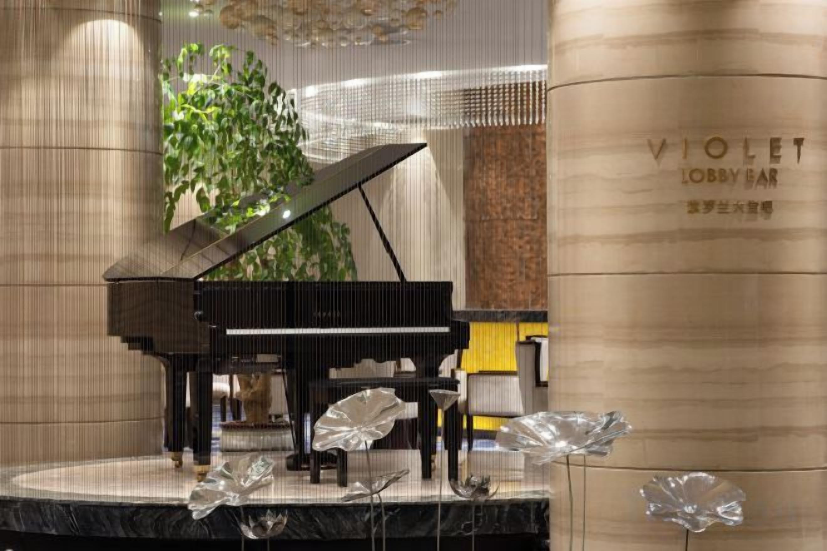 Un piano de cola en un escenario, con una columna que dice 'VIOLET LOBBY BAR' al fondo.
