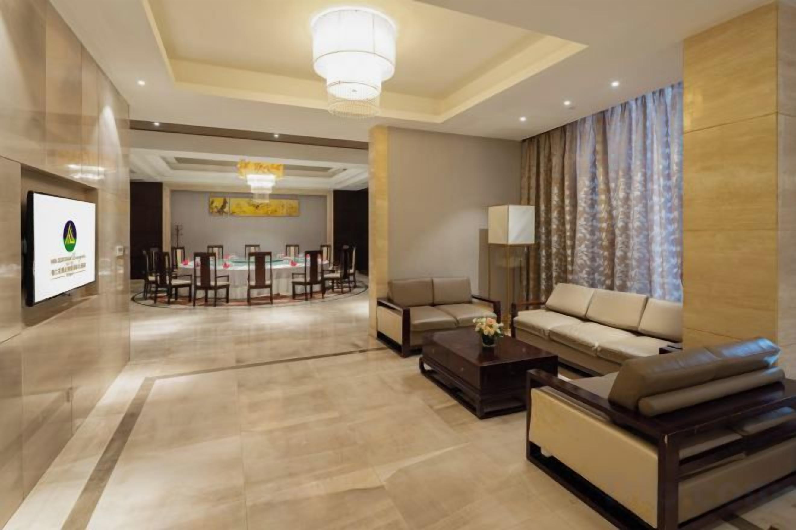 Un vestíbulo de hotel con mostrador de recepción, área de estar y una sala de conferencias.