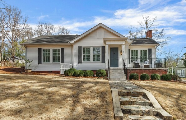 A single-story house with a front porch, a chimney, and a small front yard with a stone pathway leading to the door. - Bellwood Beauty (Northport)