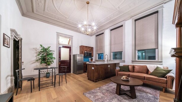 Un salon moderne avec un canapé en cuir marron, une table basse et un coin repas comprenant une petite table et des chaises.