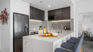 A modern kitchen with a central island, stainless steel appliances, and a dark wood finish. - Heart of the City Apartment (Auckland)