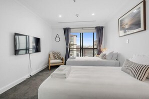 Relax in a stylish room with two single beds, a large flat-screen TV, and a comfortable armchair.
