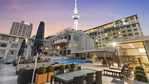 A rooftop pool area with outdoor seating and a view of a tower. - Heart of the City Apartment (Auckland)