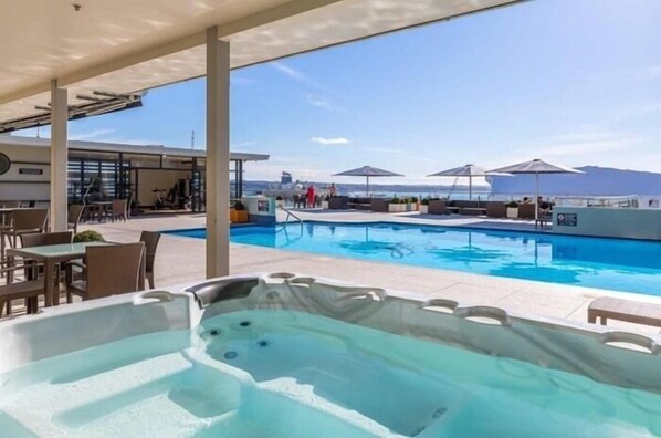 Relax by the ocean-view pool, surrounded by lounge chairs and umbrellas, and unwind in the adjacent hot tub.