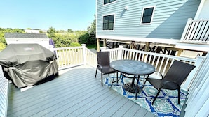 Een terras met een overdekte barbecue, een tafel en twee stoelen.