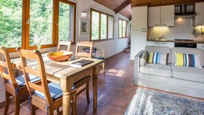 Une salle à manger spacieuse avec des chaises en bois et une grande table, un salon confortable avec un canapé, et une cuisine moderne avec des meubles blancs et une cuisinière.