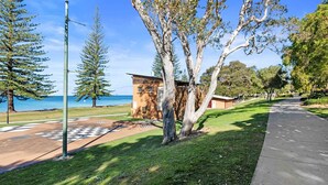 A coastal park with a small wooden structure, a paved path, and a view of the sea.