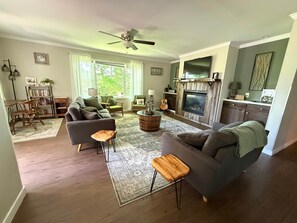 Uma sala de estar com lareira, sofá, mesa de centro e estante.