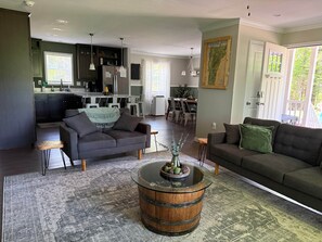 Un salon moderne avec un canapé gris foncé, une table basse ronde en bois et, au fond, un coin repas.