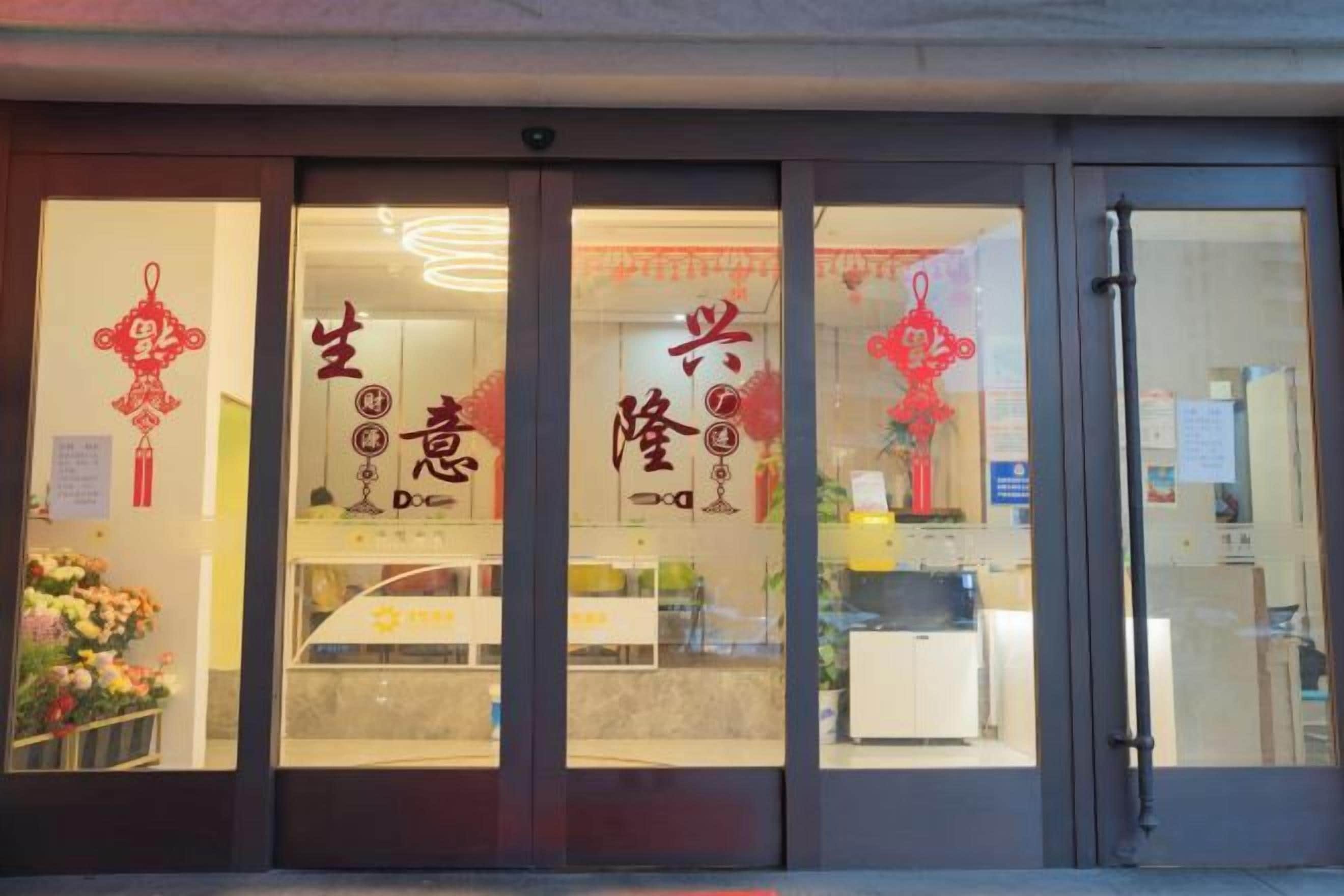 A storefront with large glass doors, Chinese characters, and a sign indicating a business.