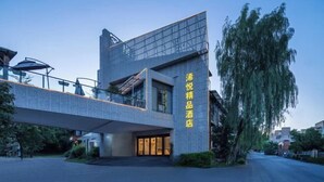 Un hotel moderno con facciata in vetro, posti a sedere all'aperto e un ingresso ben visibile con insegne.