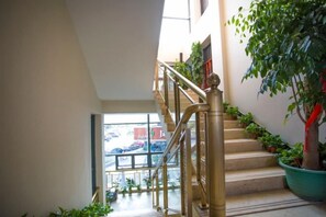A staircase with a handrail, potted plants, and a view of the outside. - Hangzhou Yue Boutique Hotel (Longhu Zijing Tianjie Sandun Subway Station) (Hangzhou)