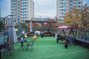 An outdoor terrace with artificial grass, a wooden pergola, a swing, and a table with chairs. - Hangzhou Yue Boutique Hotel (Longhu Zijing Tianjie Sandun Subway Station) (Hangzhou)