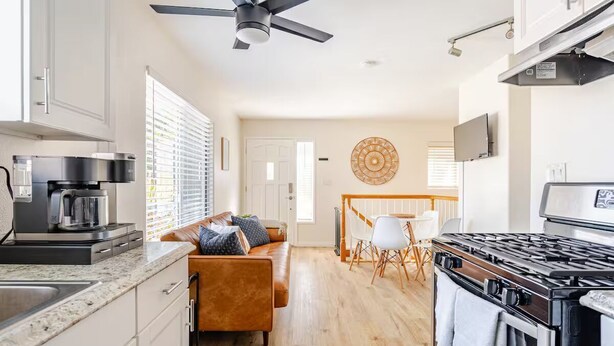 Una cocina moderna con estufa, cafetera y comedor con mesa y sillas.