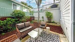 Un patio con muebles de mimbre, un tapete estampado y una mesita.