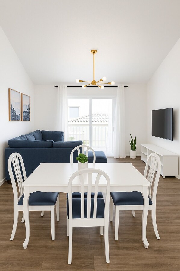 A modern living room with a sofa, dining table, chairs, a TV, and a ceiling light.