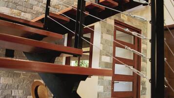 Una escalera de madera con un fondo de pared de piedra y una puerta en la parte superior.