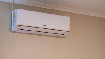 Un equipo de aire acondicionado blanco instalado en la pared, con panel de control y luz indicadora de encendido.