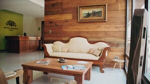 A wooden-floored lobby with a reception desk, a sofa, and a coffee table with magazines. - Hotel Madero Talca (Talca)