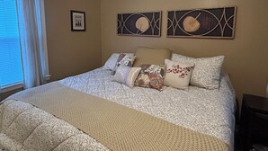 Ein Schlafzimmer mit einem großen Bett, beigen Wänden und zwei Wandbildern.